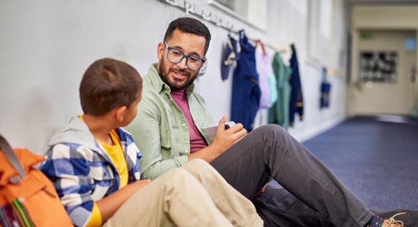A woman in a small boutique shop talks on the phone while working on a laptop at a wooden counter surrounded by woven baskets and home decor items