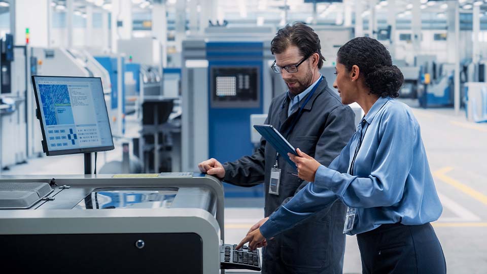Two professionals review data on a screen inside a semiconductor manufacturing facility.