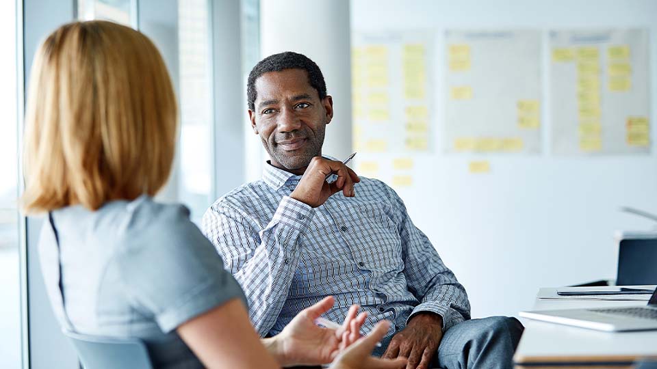 Businessman smiling at woman during discussion in office conference room