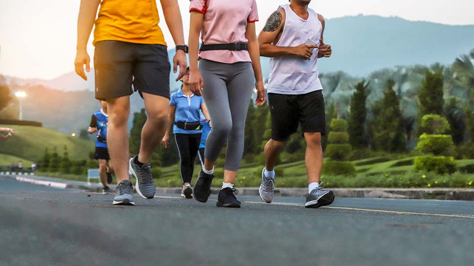 A group of people walking and jogging on a paved road