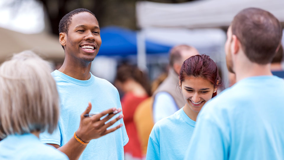 Man in blue shirt holding clipboard talking with other people in blue shirts